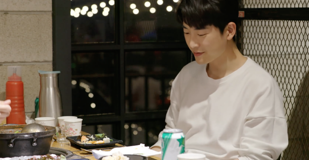 兩人在海邊餐廳享用海鮮，面朝窗外寧靜的海景，餐桌上有多種韓式海鮮料理。