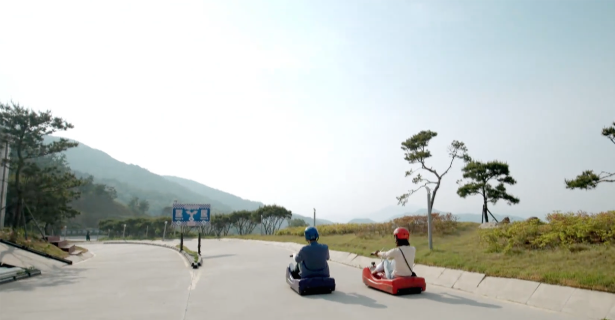 滑車遊戲中的戶外風光，開闊的道路兩旁樹木點綴，展示了一種自由的感覺。