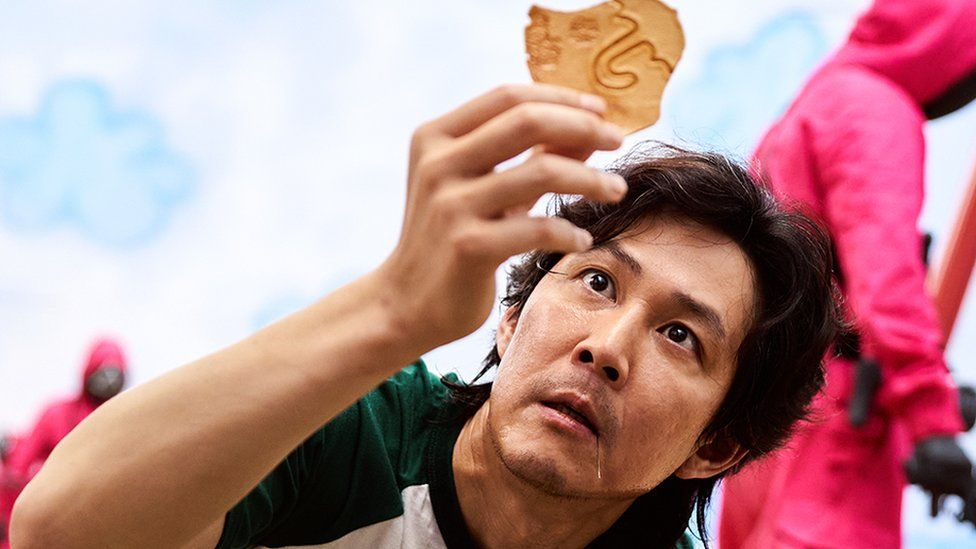 韩国大受欢迎的电视剧《鱿鱼游戏》剧照，游戏道具椪糖（Dalgona）在聚光灯中成为国际热门话题。此游戏增强了椪糖在全球的认知度，引发对韩国文化的讨论，并被牛津词典收录。