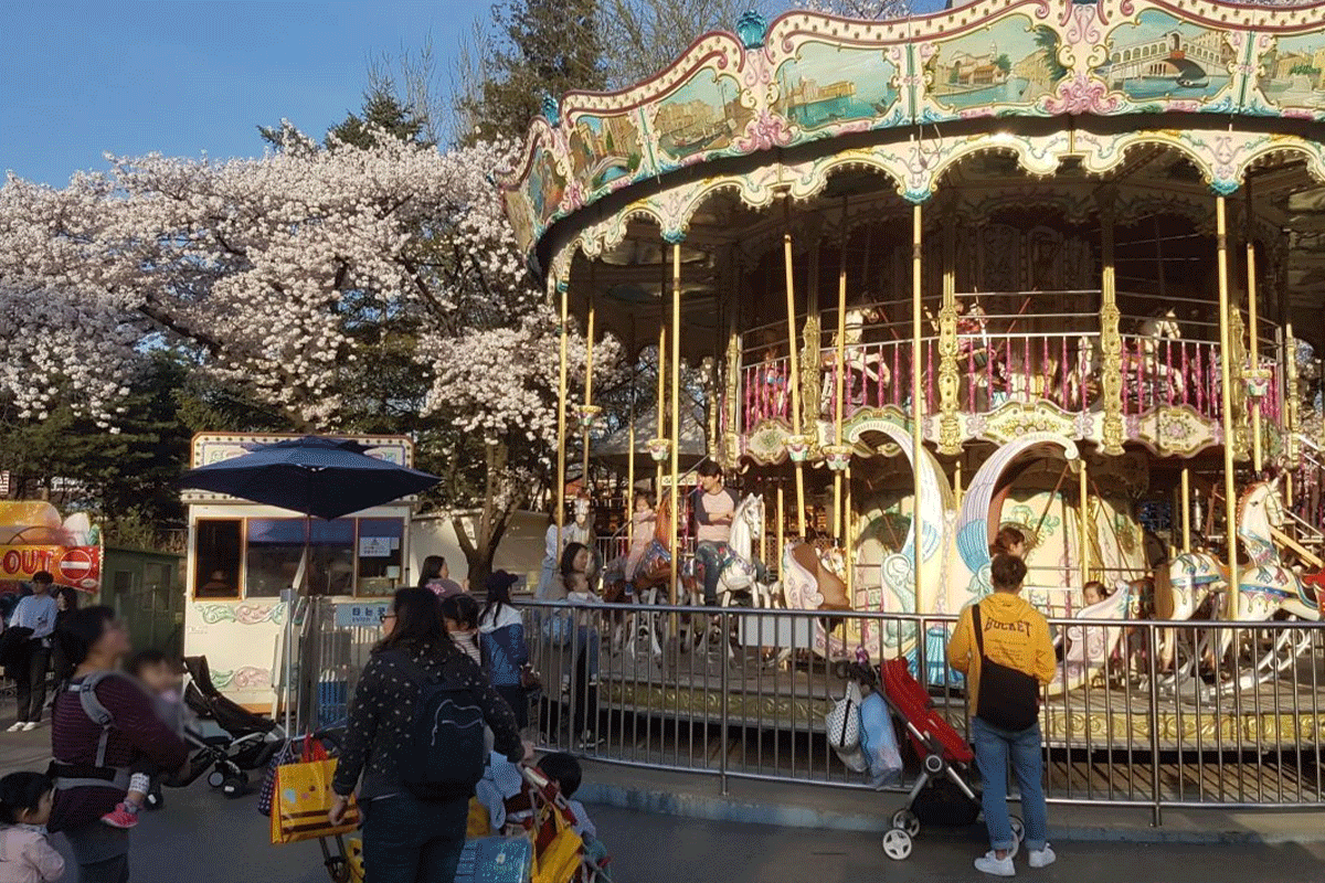 子供大公園のメリーゴーラウンド。楽しそうに遊ぶ人々の様子。