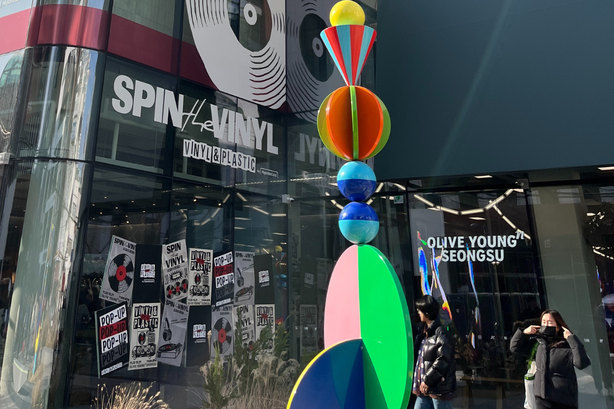 一座位於首爾聖水洞的OLIVE YOUNG N大廈，展示著其現代的建築外觀及入口處的時尚招牌。