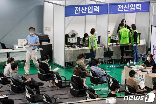 韩国疫苗接种中心，市民正有序等待疫苗接种，工作人员忙碌于信息登记与疫苗分发省。