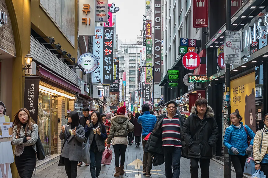 韩国首尔的繁华购物街，街道两旁布满了各种商店，行人络绎不绝，展示了城市的活力与购物文化。