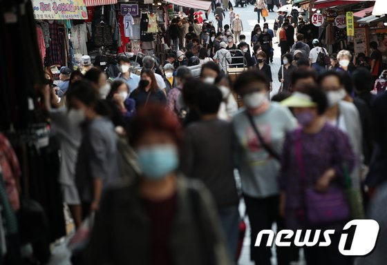 韩国繁忙市场中的人群，大家都佩戴着口罩遵守防疫措施
