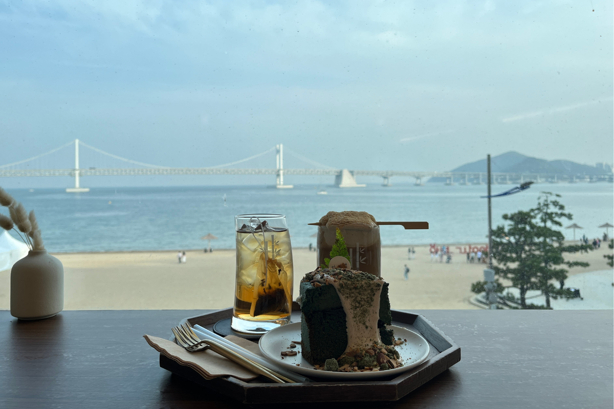 View of Gwangan Bridge from a cafe in Busan, featuring drinks and a mugwort gateau cake.