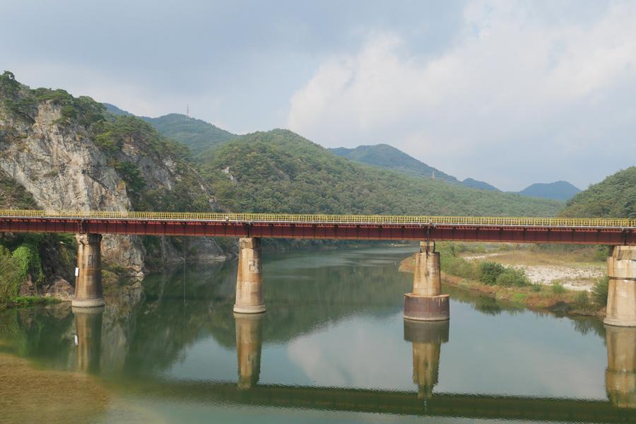 古老橋梁橫跨在江面上，對岸的綠意盎然景緻令人心曠神怡。