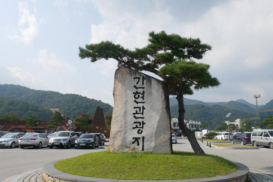 艮峴觀光地入口大石，吸引著遊客的視線，背景是青翠的山脈與停車場。