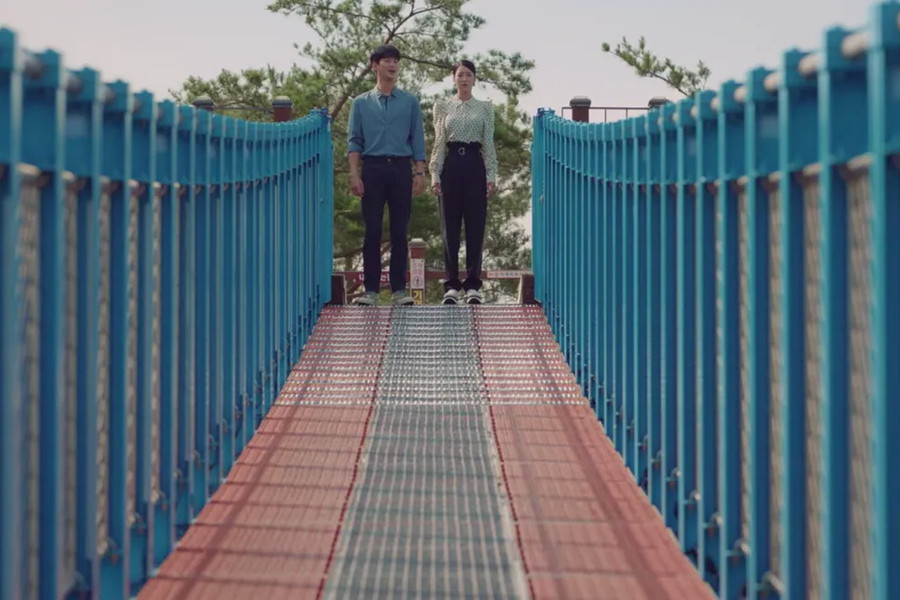 小金山懸索吊橋上兩位遊客正在欣賞美景，顯示出此景點的受歡迎程度。