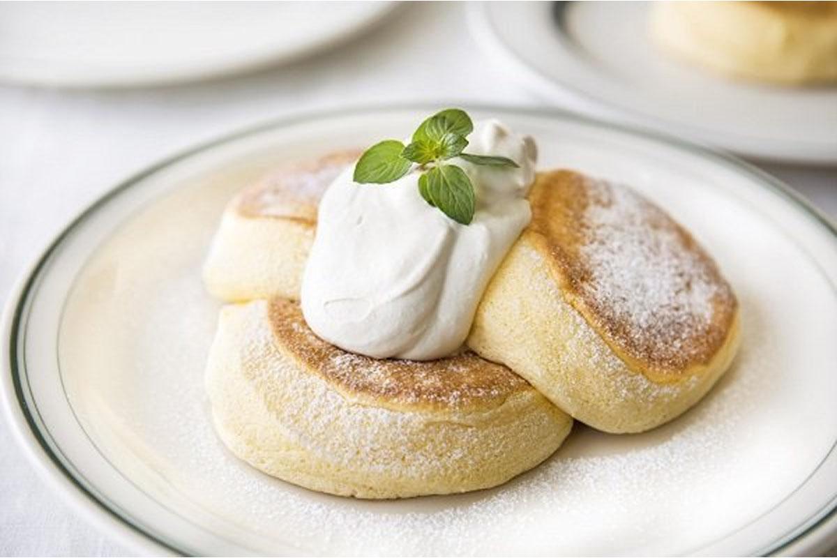 ภาพของแพนเค้กซูเฟลญี่ปุ่น ที่มีลักษณะนุ่มและเด้งพร้อมท็อปด้วยวิปครีมและใบสะระแหน่ด้านบน แสดงถึงความนุ่มของขนมที่นิยามในหมู่คนเกาหลี