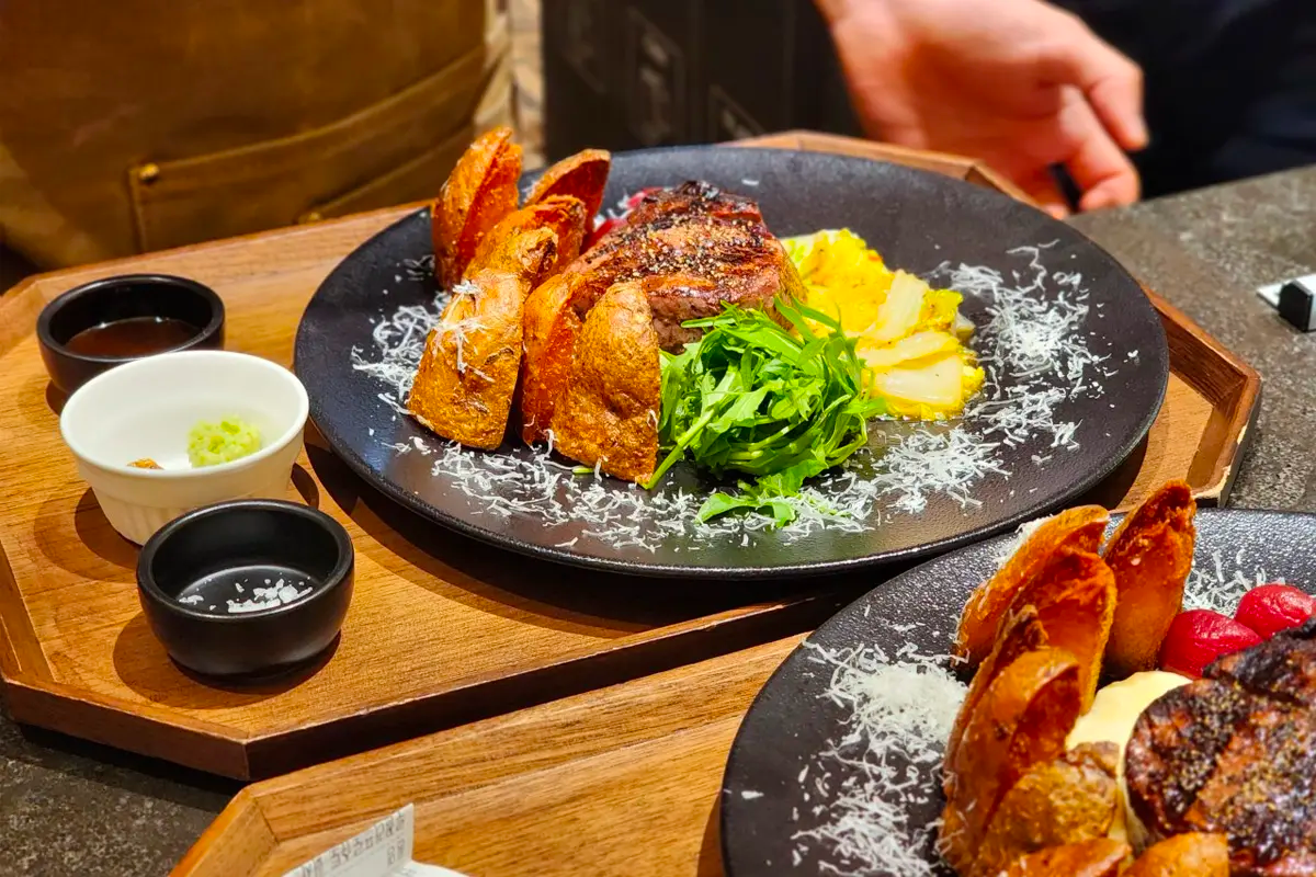 大满月餐厅招牌菜品，木盘上摆放的西餐成果，搭配新鲜调味料和香草装饰，呈现高档美食体验。