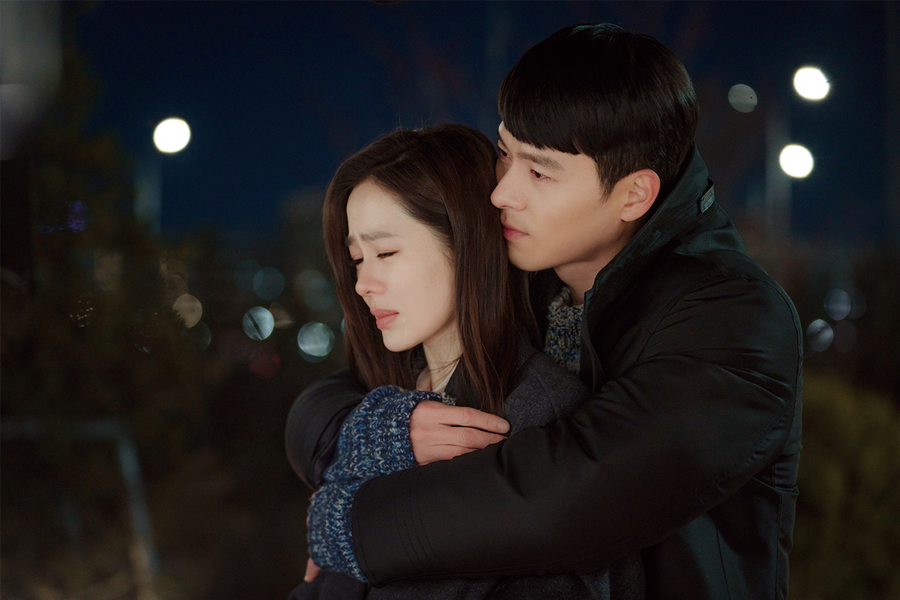 韓劇《愛的迫降》中，兩位主角在夜晚擁抱，背景是燈光點點的城市景象，創造出溫馨感人的畫面。