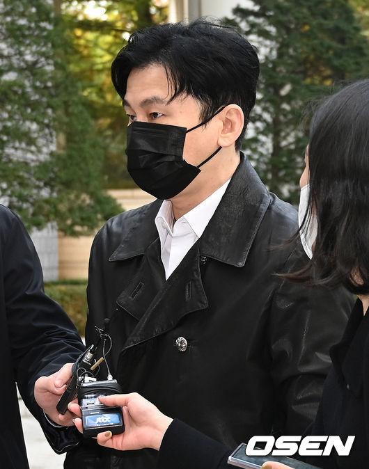 報道陣に囲まれる黒いジャケットを着た男性、法廷に到着