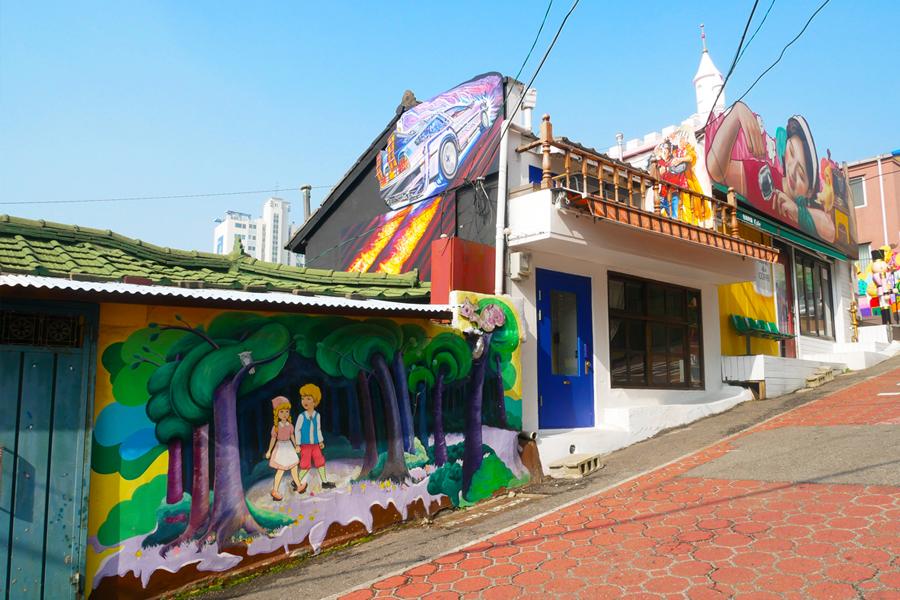 松月洞童話村內，一幅色彩豐富的花卉和海景壁畫，吸引遊客拍照。