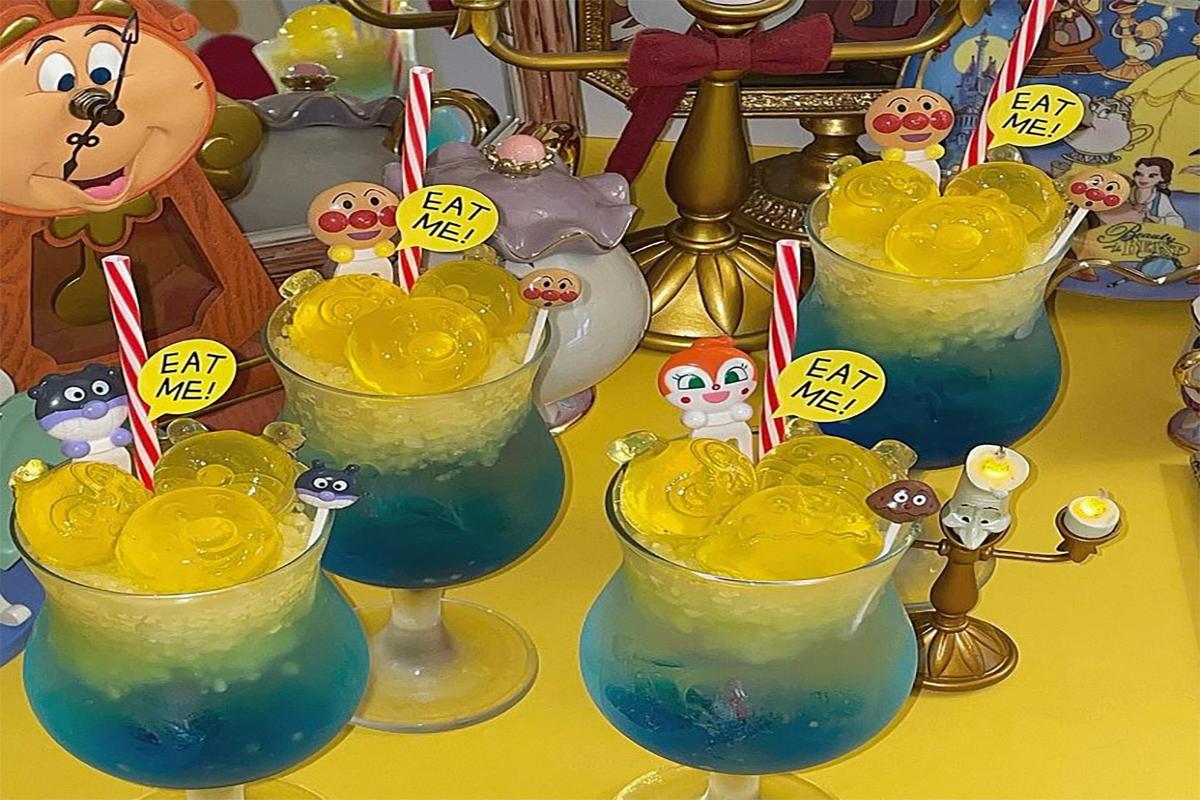 Kreative Anpanman Limonaden im Yeonhee Coffee, Seoul. Drei bunte Getränke verziert mit Anpanman-Gelees, gelben Emojis und 'Eat Me!' Schildern, auf einem Tisch dekoriert mit Disney-Figuren.