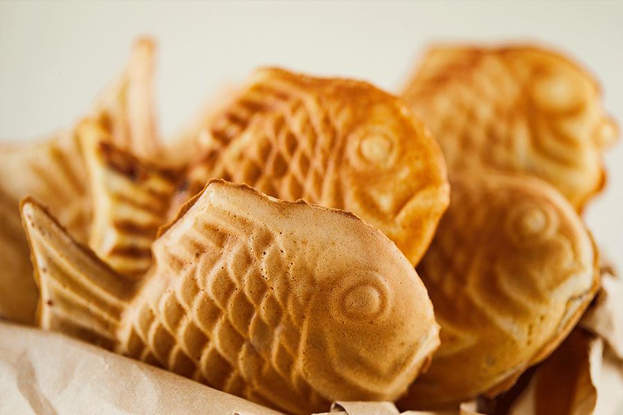 韓國街頭小吃鯛魚燒，幾個金黃色的魚形麵包裝在紙袋中。