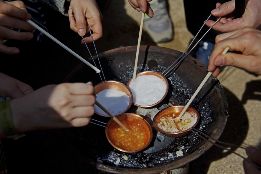韓國傳統零食“椪糖”的製作過程；一群人圍著糖和小蘇打的混合物加熱，準備製作椪糖。