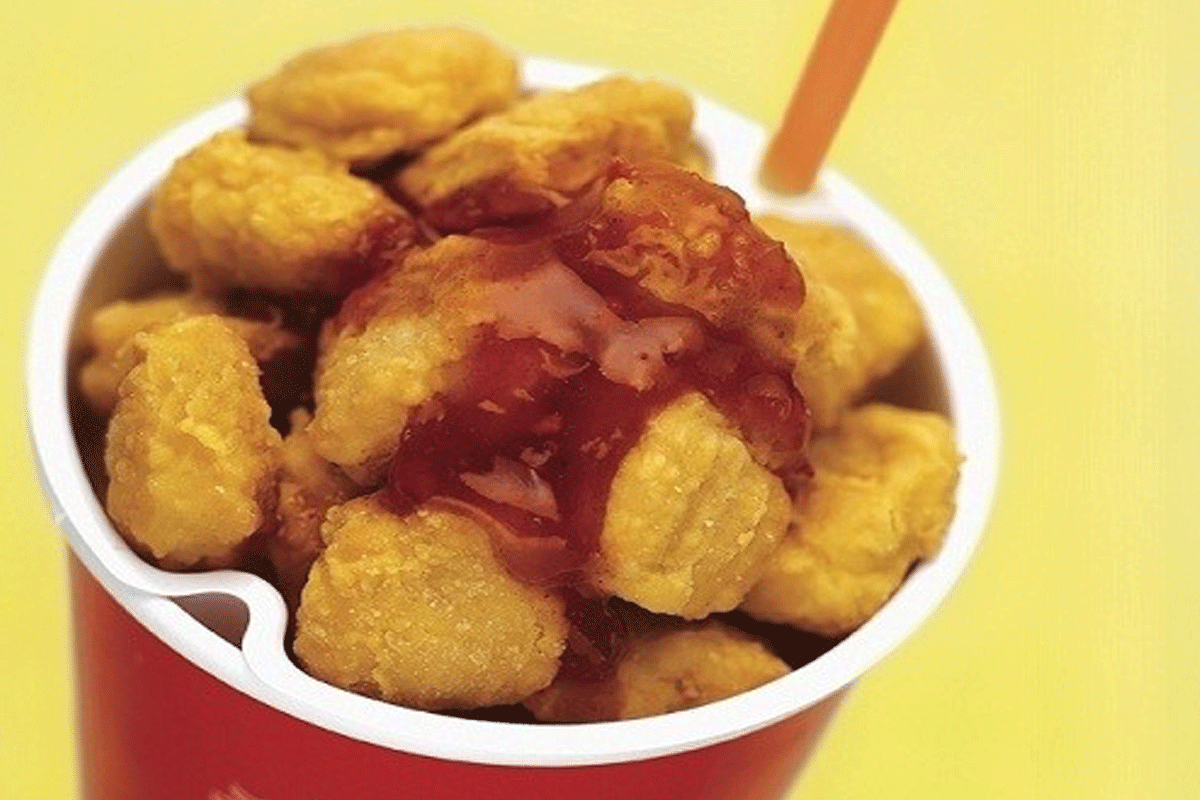 コップに入れられた韓国のコルポップチキン、ソースがかかったポップコーンサイズのチキンピース