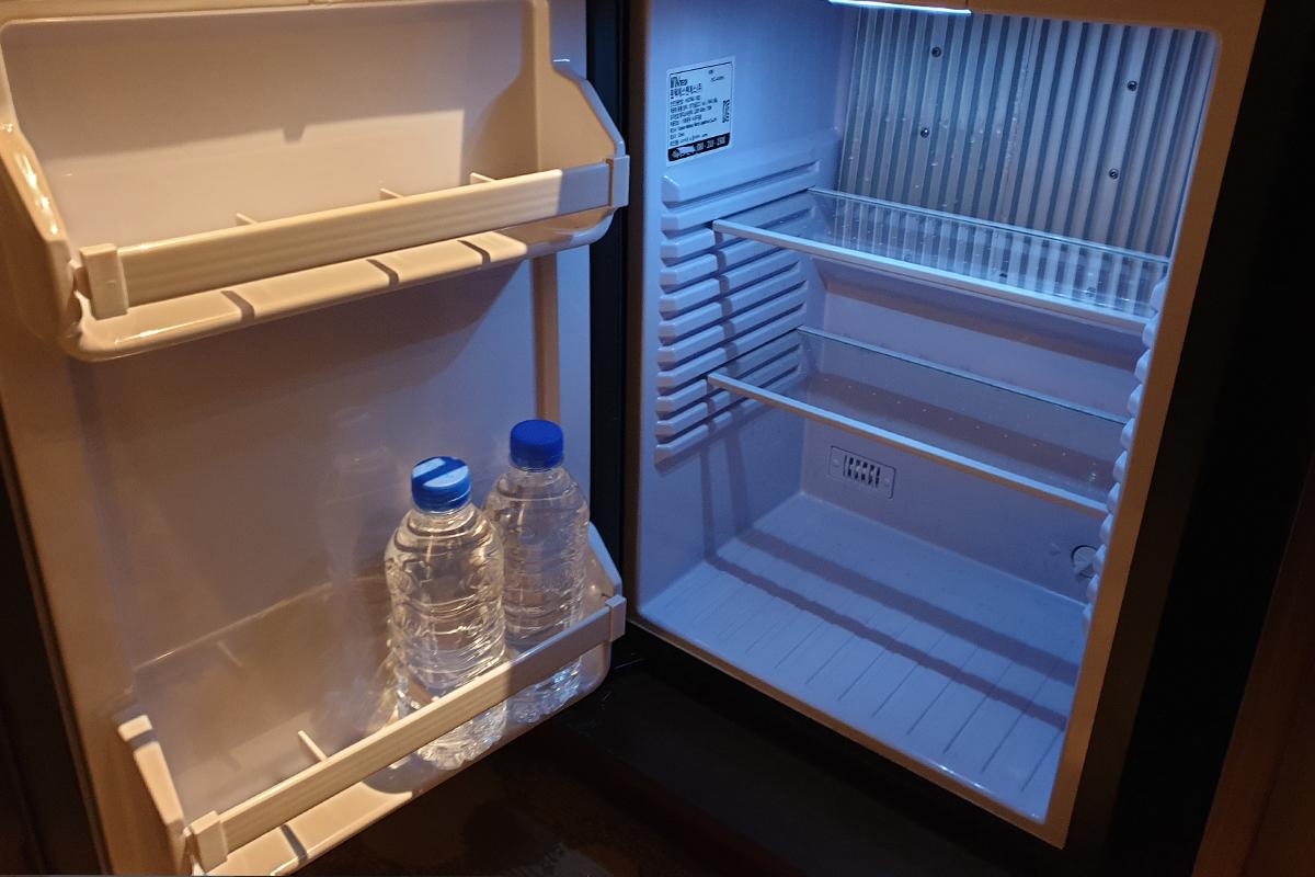 An open mini fridge that is stocked with two water bottles.
