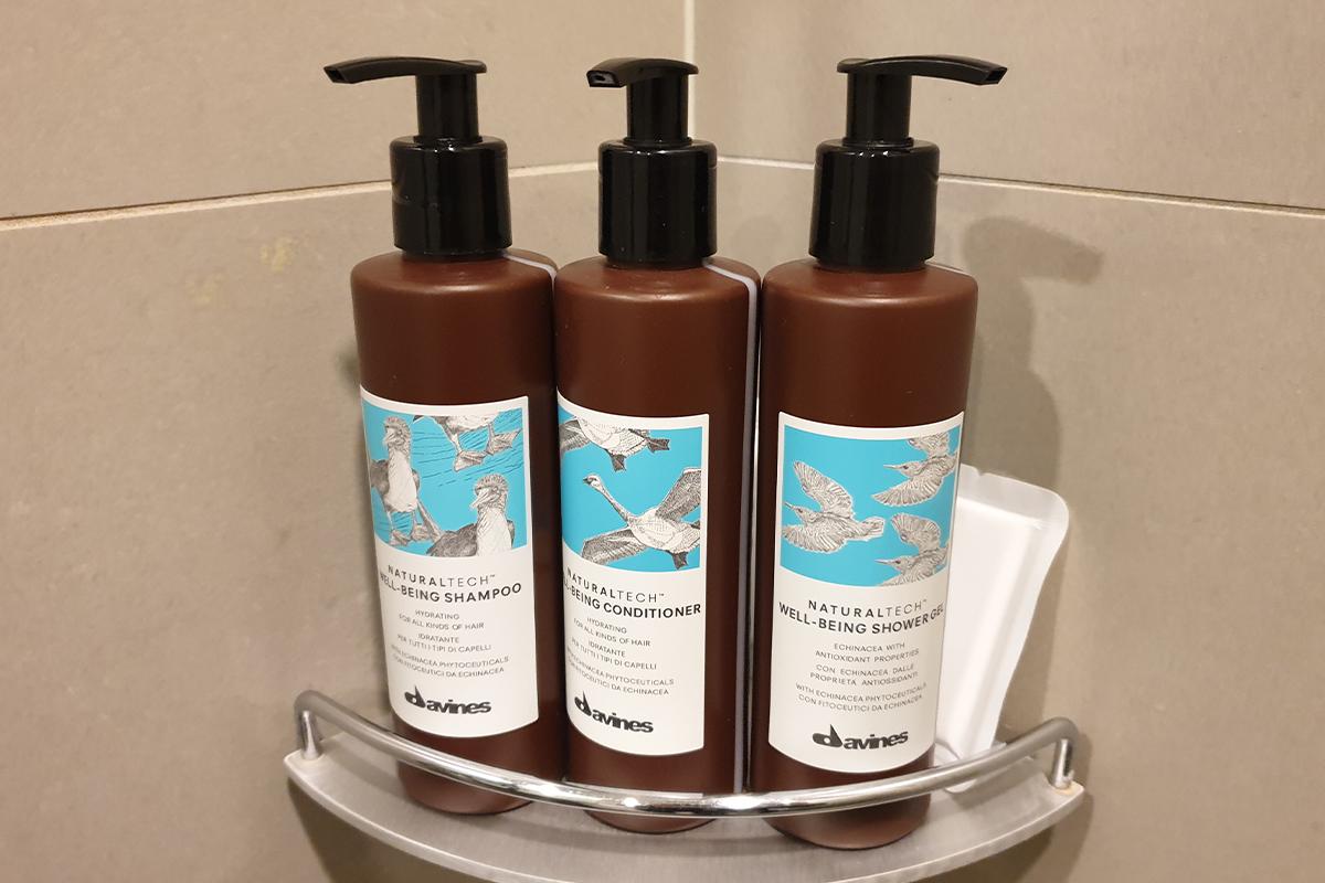 Shampoo, conditioner, body wash and a sponge in the shower.