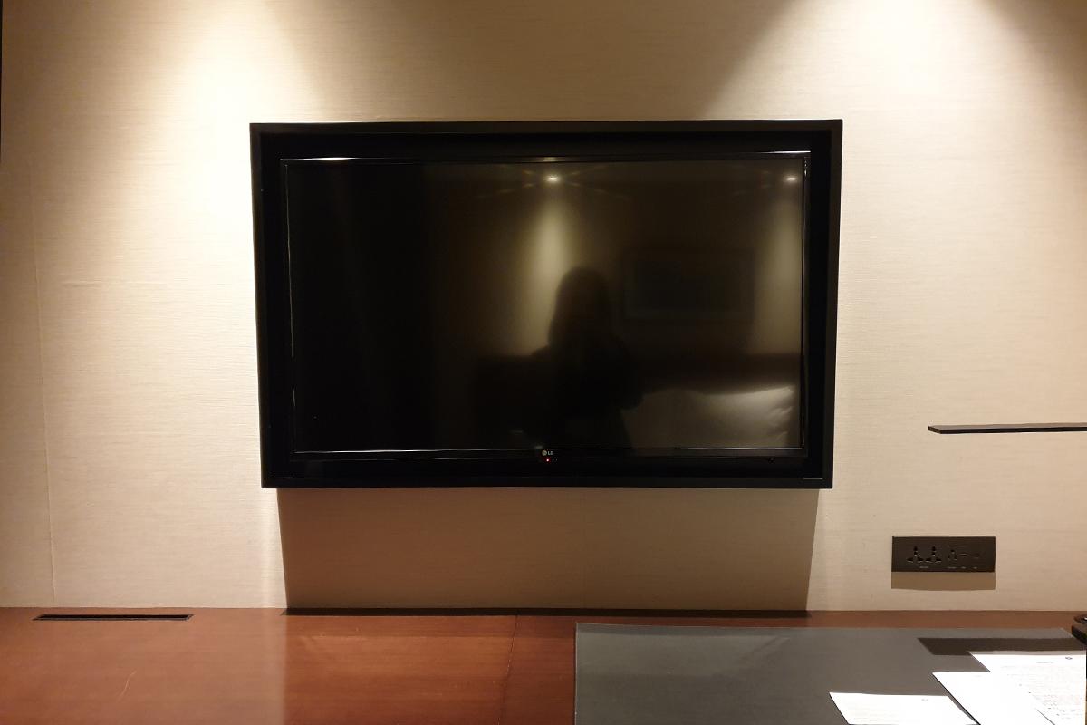 A TV is mounted on the wall above a desk.