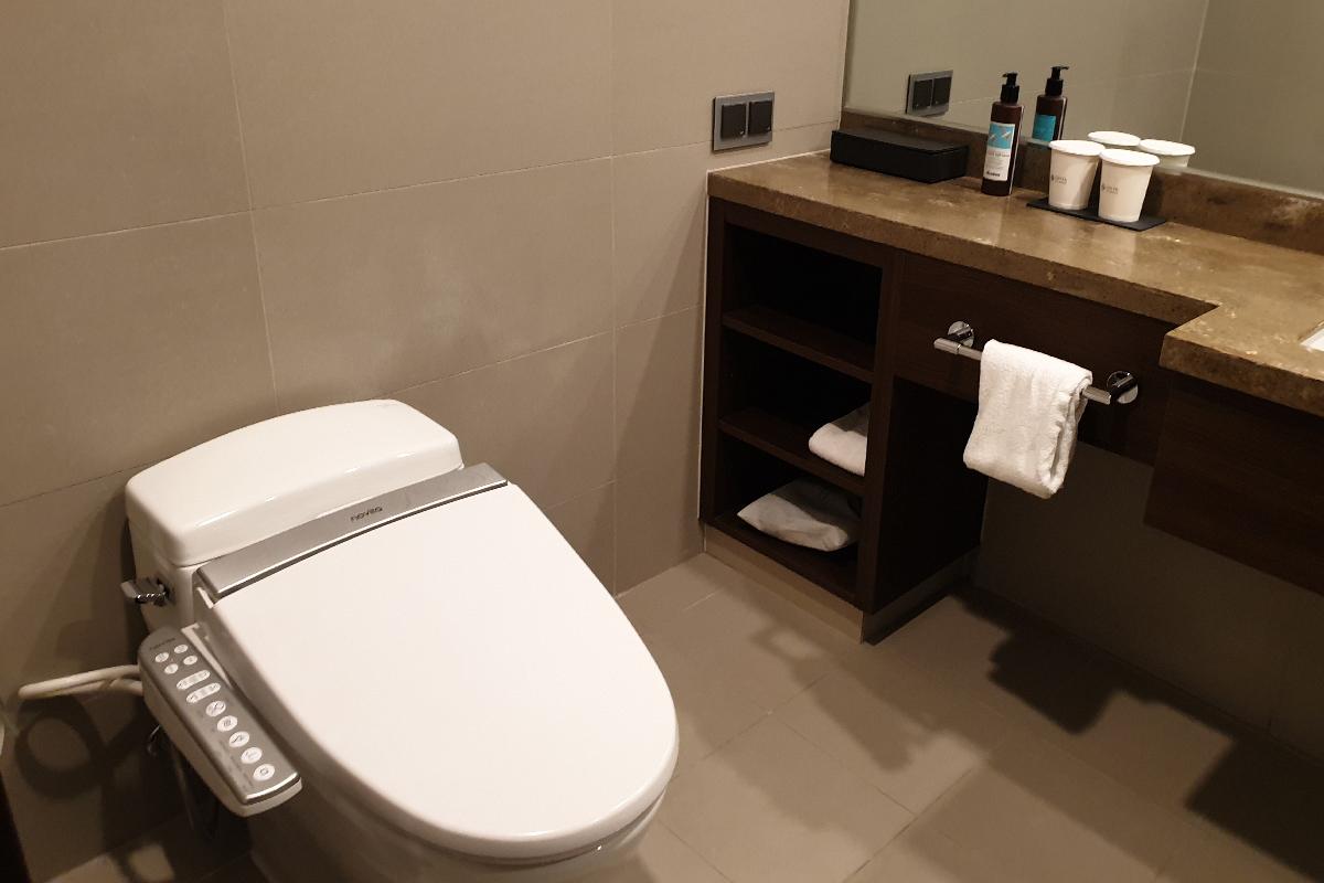 A toilet with an electric bidet and a view of the bathroom counter.