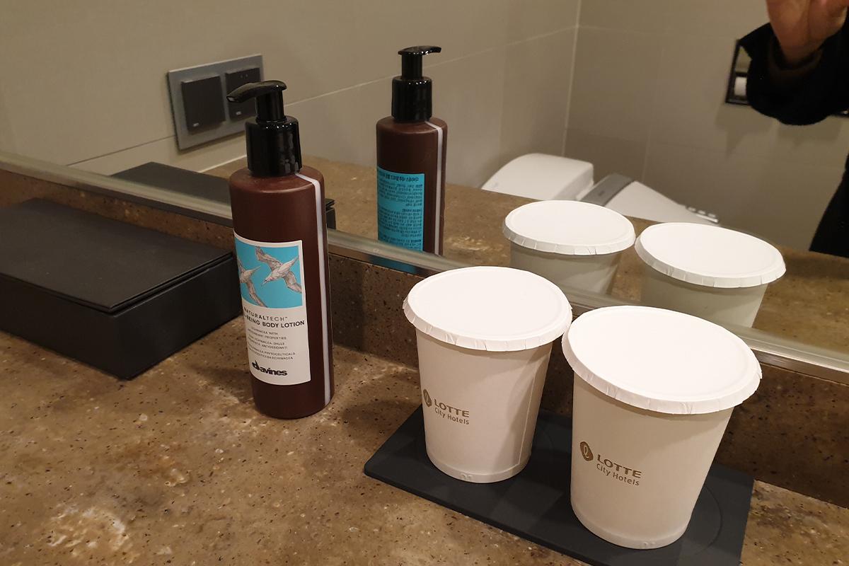 Lotion and cups available for use in the bathroom.