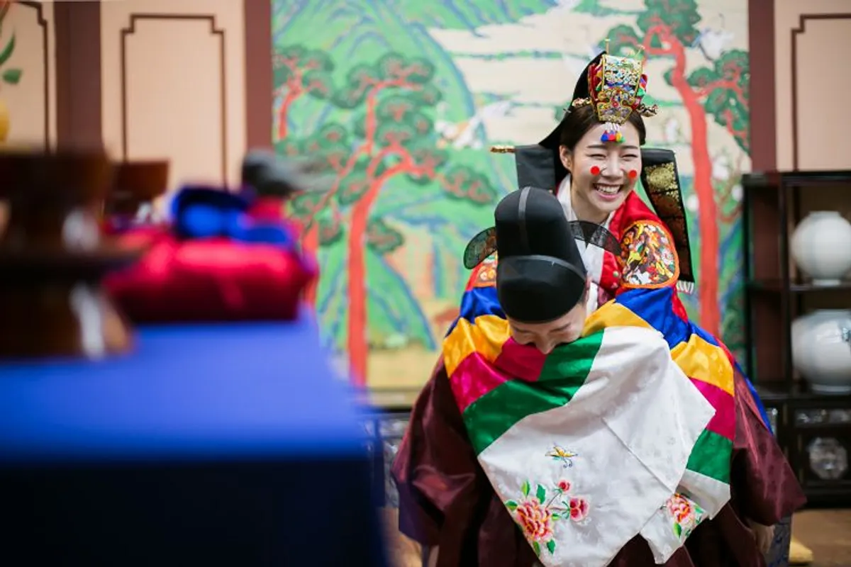 韩国传统婚礼的一个场景，新娘穿着色彩缤纷的婚礼礼服，背对观众。