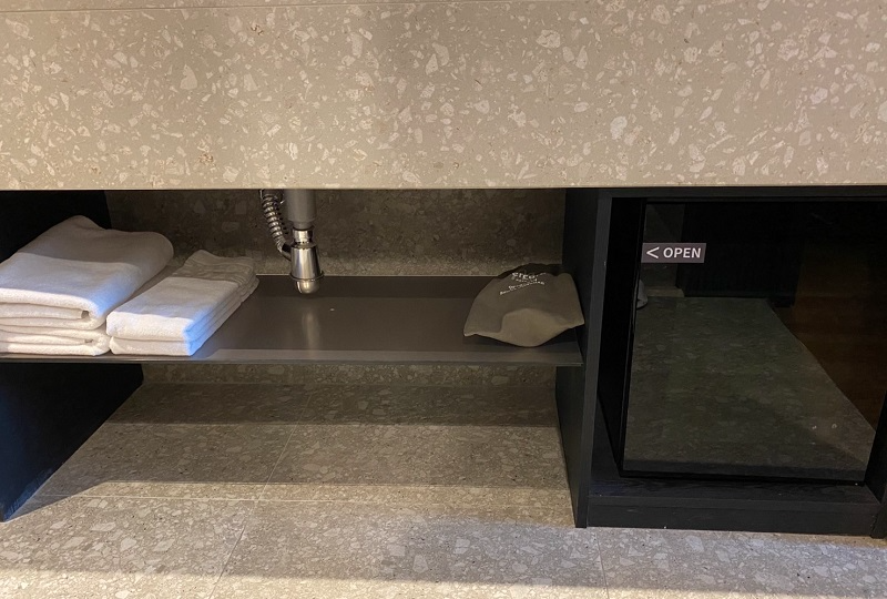 洗面台下の棚に配置されたタオルとドライヤー。