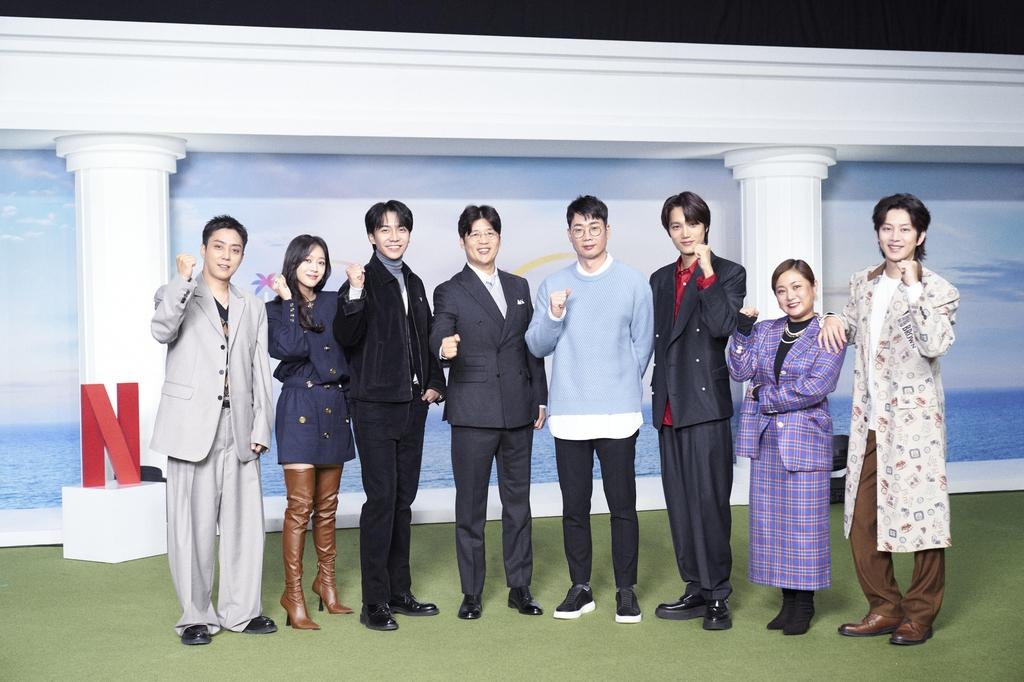 Netflixの新バラエティ番組『ニュー・ワールド ～ここは新世界～』の出演者たちが直立してポーズをとる。背景にはNetflixのロゴと海が描かれている。出演者は多彩な衣装を着用し、個性豊かなスタイルを披露している。