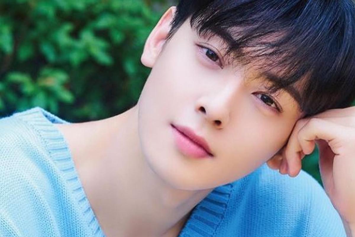 Chàng trai mặc áo len xanh, tạo dáng trên nền cây xanh.