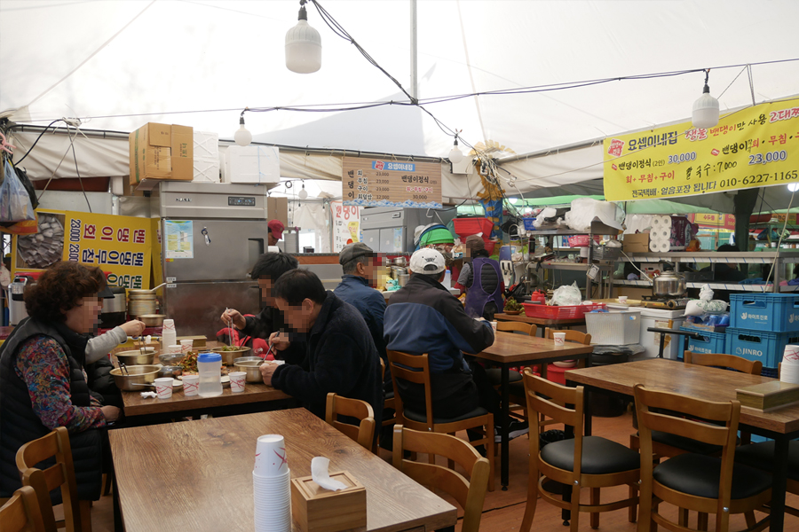 강화풍물시장의 간이 식당 – 전통적인 한식을 제공하는 작은 식당에서 손님들이 식사를 즐기고 있는 모습