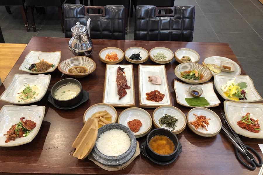 Traditional Korean meal set in Geogung restaurant, Songdo, Incheon, with various dishes and sides beautifully arranged on a table.