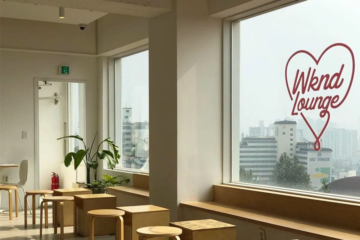 Spacious interior of wknd lounge cafe in Incheon, featuring natural lighting and minimalist wooden furniture.