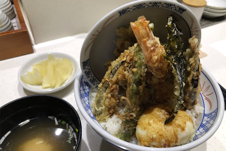 A bowl of ONSEN Tendon with tempura shrimp and vegetables over rice, served with soup in a Japanese restaurant in Songdo, Incheon.