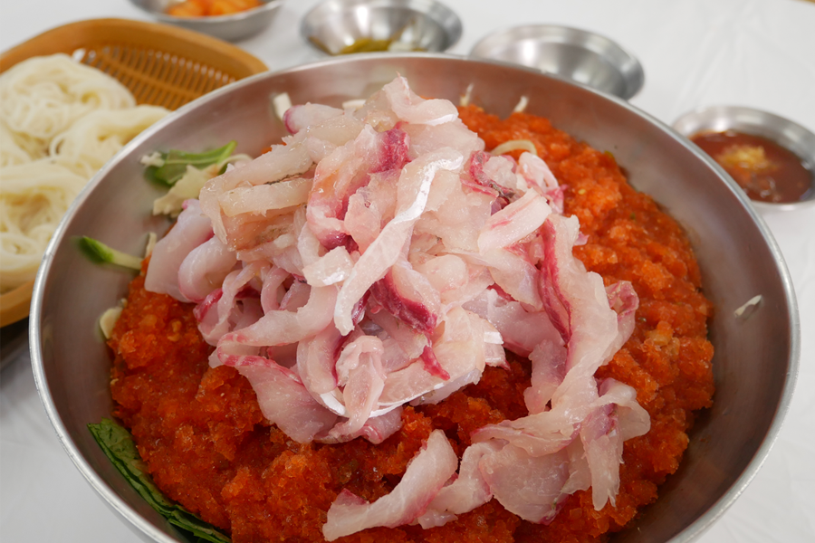 A bowl of Hwedupbap (Korean-style sashimi rice bowl) with fresh fish slices on top of finely crushed ice at a seafood restaurant in Incheon.