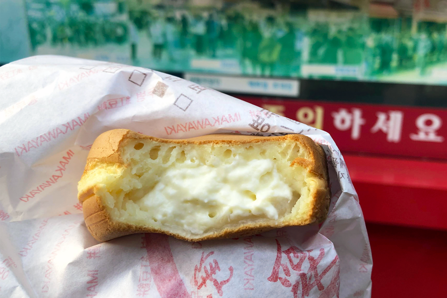 A close-up of a Hoddeok filled with creamy cheese from a popular sweet shop in Incheon
