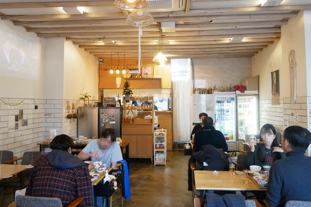 Inside view of a cozy dining area at a restaurant in Incheon, South Korea, with wooden beams and ambient lighting creating a warm atmosphere.
