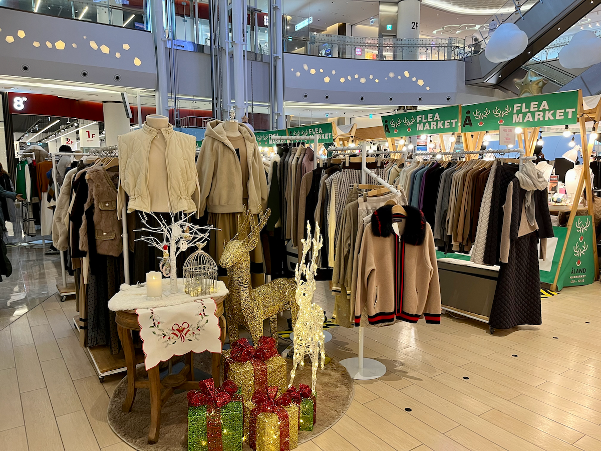 Mercato delle pulci all'interno del Lotte World Mall, Seoul, con capi invernali in vendita e decorazioni.