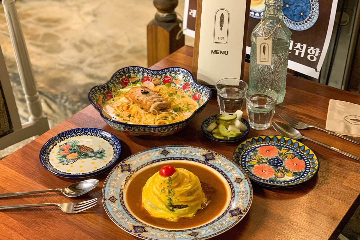 Bàn ăn tại nhà hàng ở Ikseondong, Seoul, với các món mì pasta sốt kem cay và cơm chiên cuộn trứng bày trí đẹp mắt, mang hương vị đặc biệt hấp dẫn.