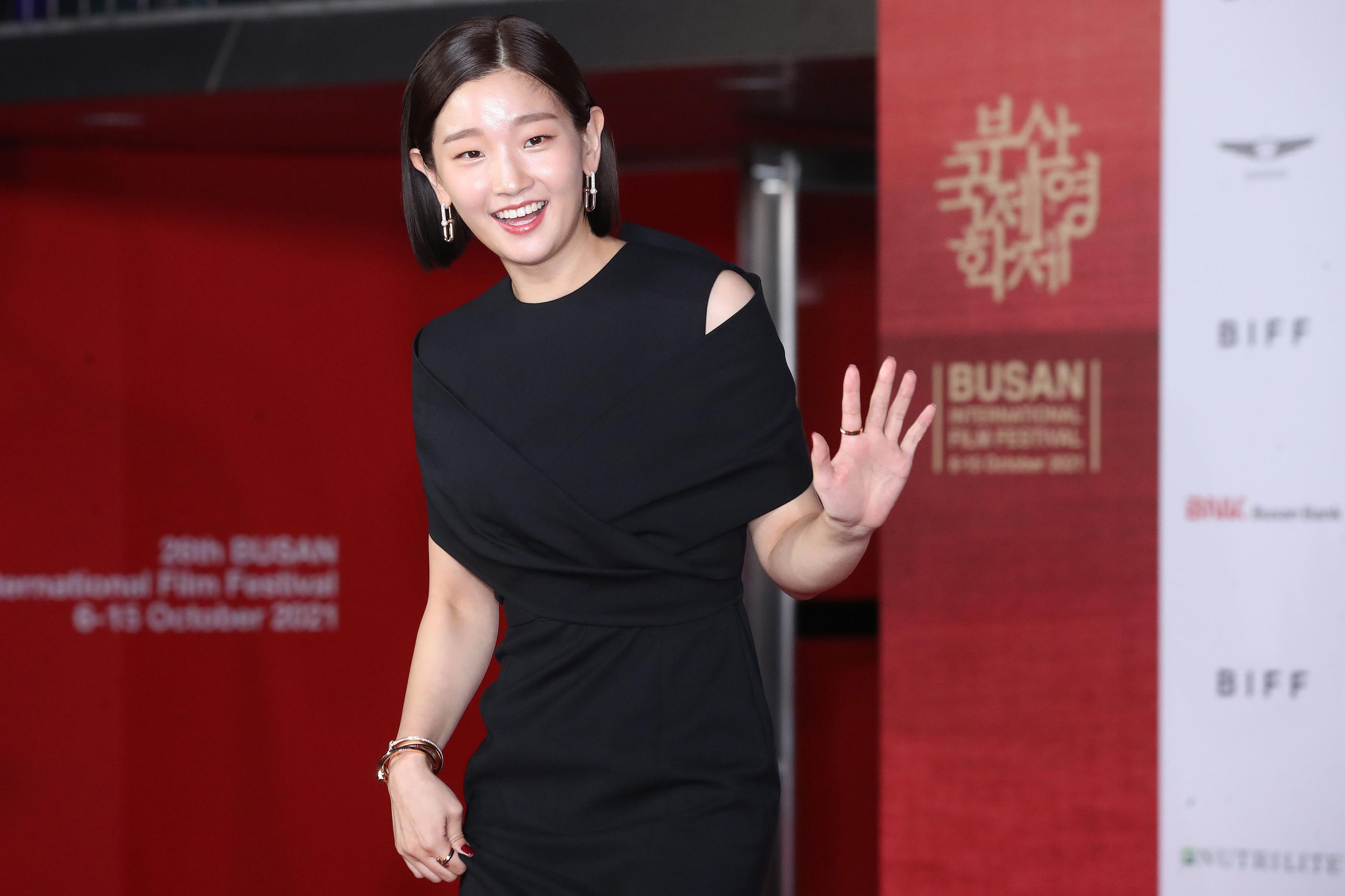 釜山国際映画祭に出席する俳優、黒いドレスを着た女性の姿。背景に映画祭のロゴが描かれています。