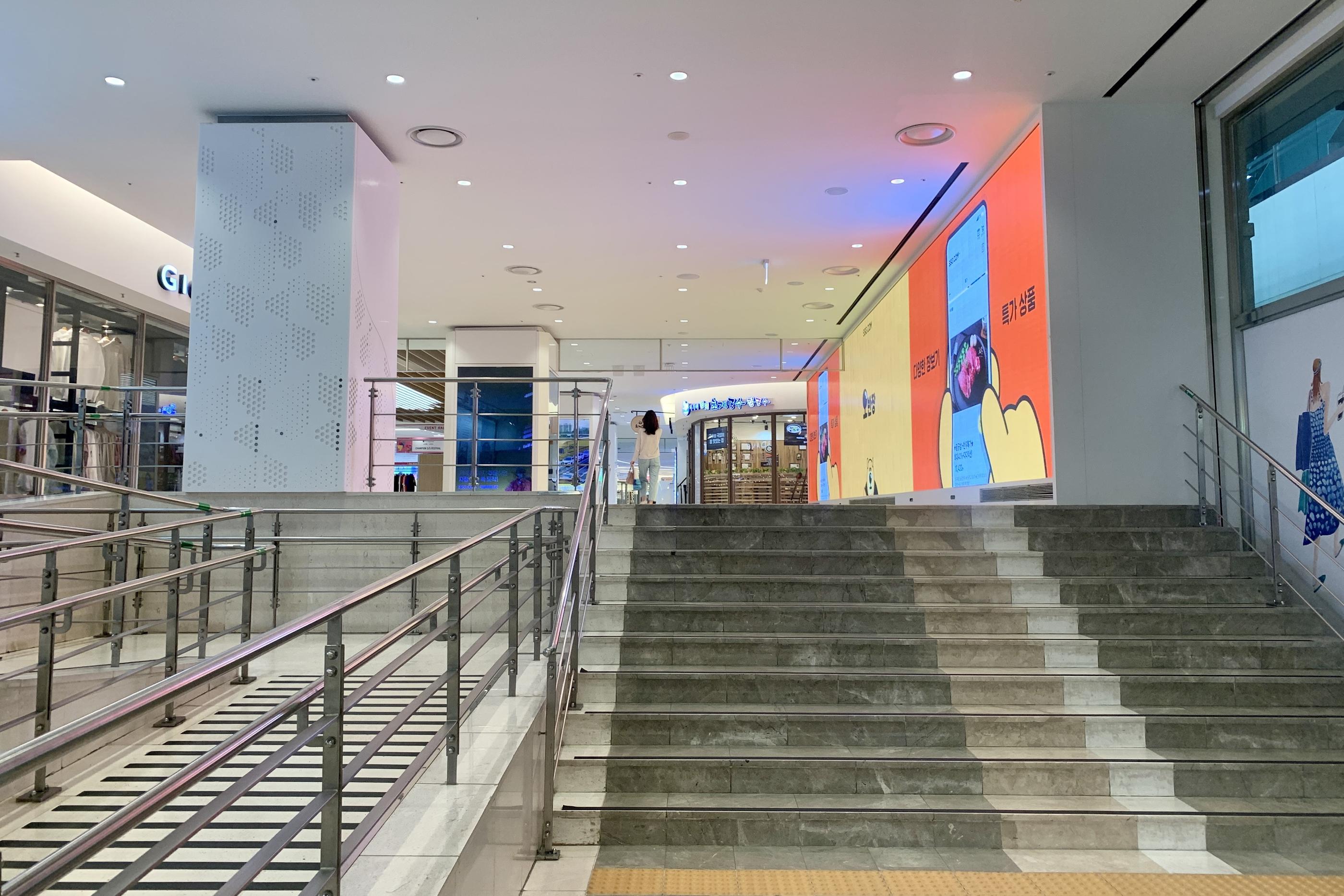 코엑스몰 내부를 보여주는 이 사진은 깔끔하고 현대적인 디자인의 쇼핑 공간을 특징으로 하며, 넓고 환한 통로에는 고객들이 주변을 둘러보는 모습이 담겼다. 주변에는 다양한 매장들이 있어 쇼핑의 기회를 제공한다.