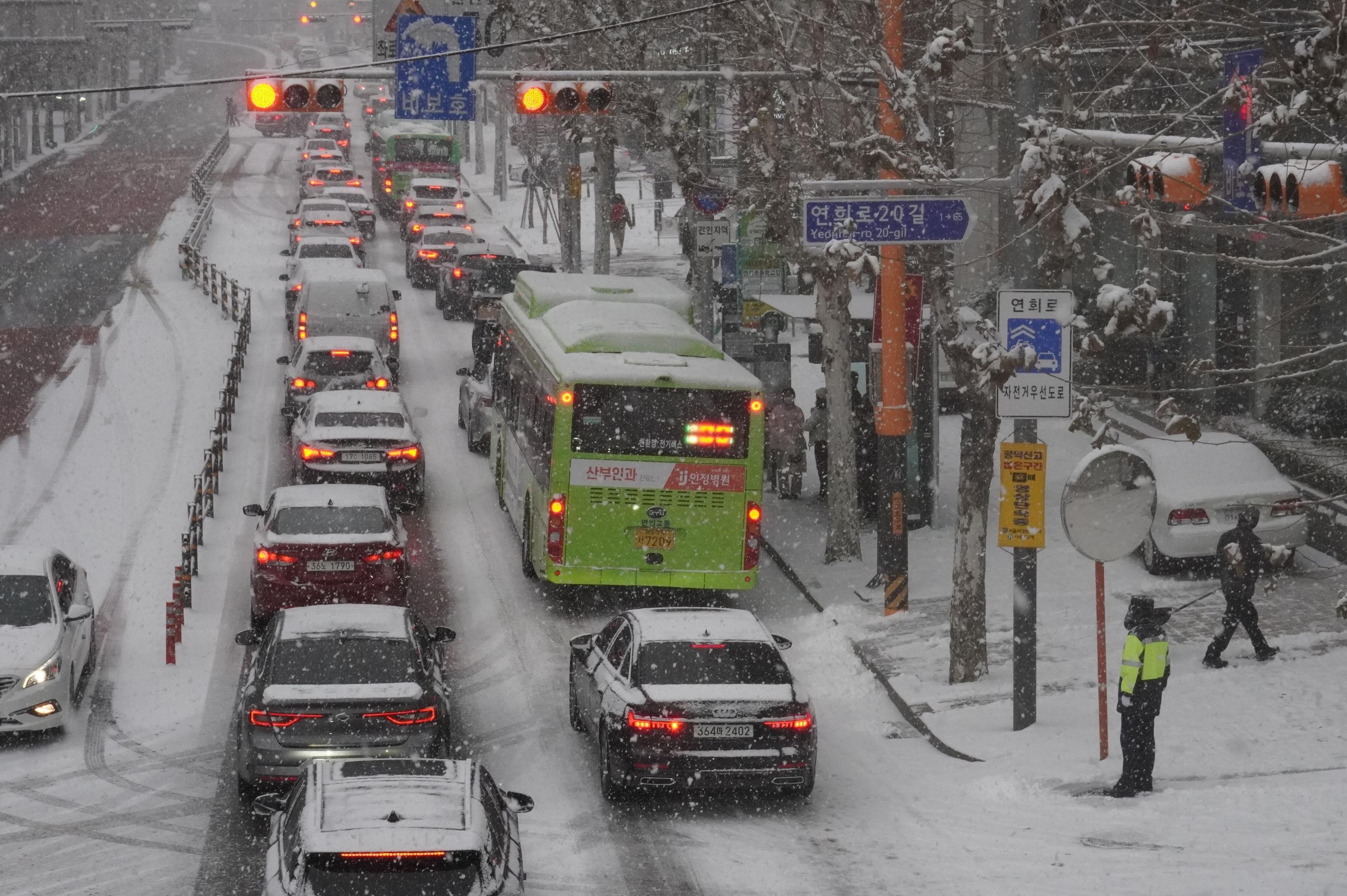 ソウルの延禧洞で大雪の中、交通渋滞に直面する車両群。警察官が道路指導を行う様子。