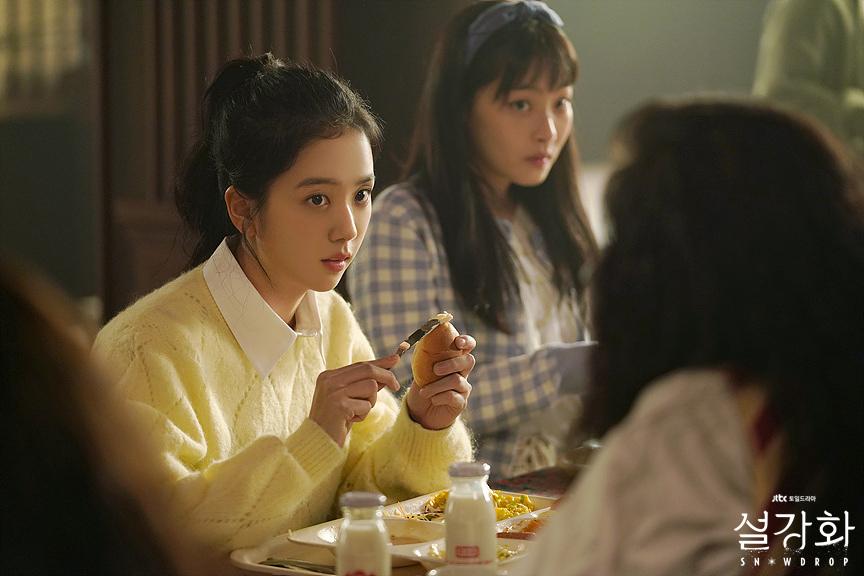 ฉากในห้องโรงอาหารที่มีภาพนักศึกษาในชุดเสื้อไหมพรมสีแดง รับประทานอาหารพร้อมพูดคุยกันในซีรีส์ Snowdrop