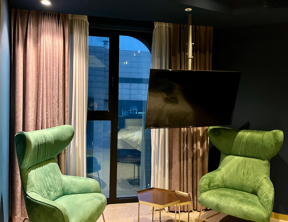 Komfortabler Entspannungsbereich mit grünen Sesseln und großem Fenster im Hotelzimmer.