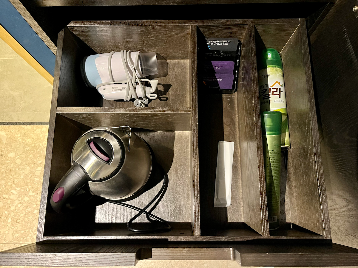 Schublade mit Zubehör wie Wasserkocher und Fön im Hotelzimmer.