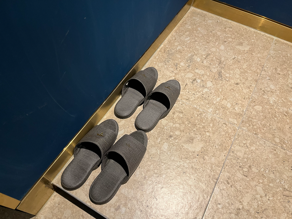 Knöpfelose Hausschuhe auf dem Marmorboden im Hotelzimmer des The Castle.