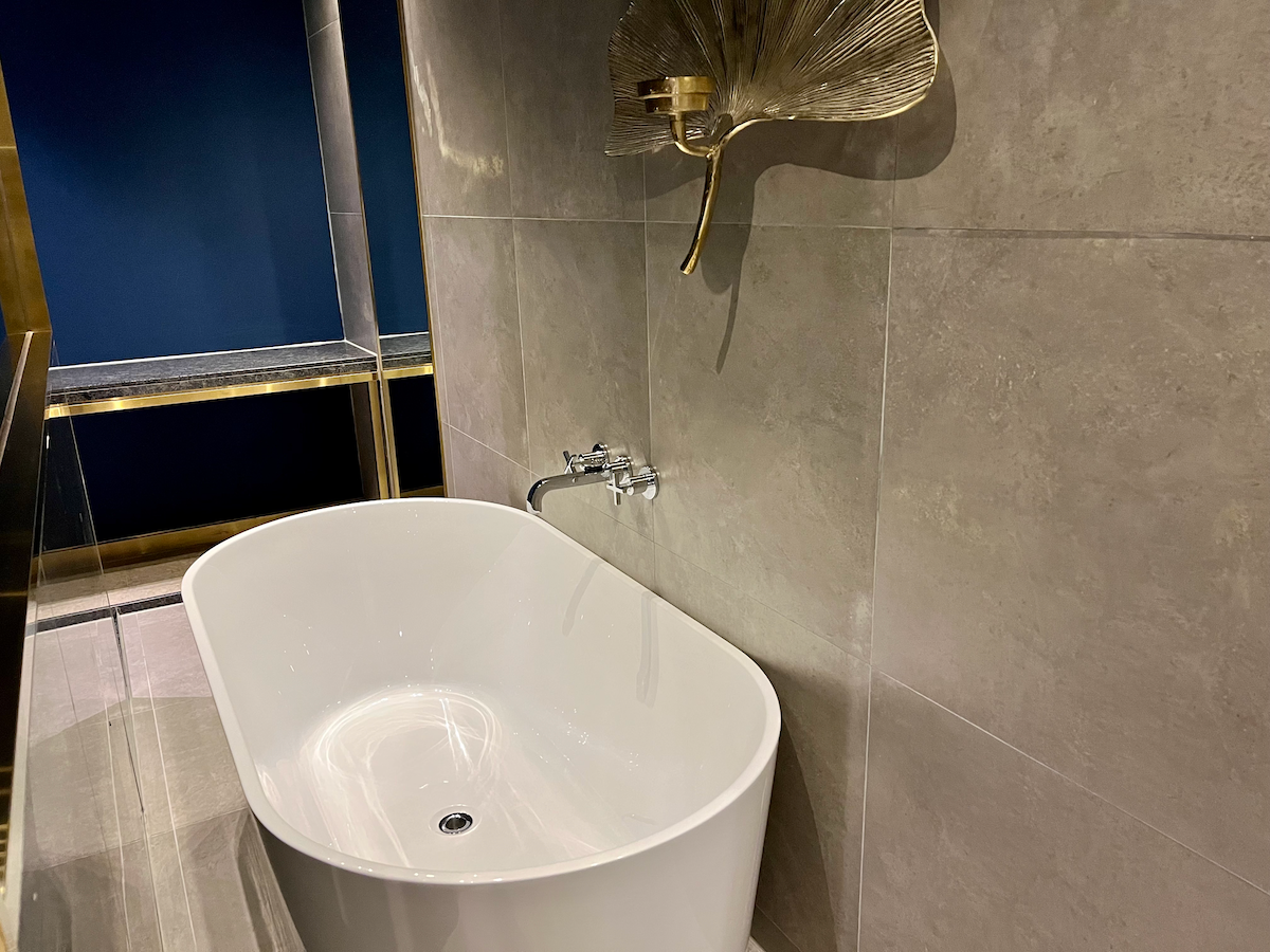 Freistehende Badewanne neben einem blauen Wandgefühl im Hotelzimmer.