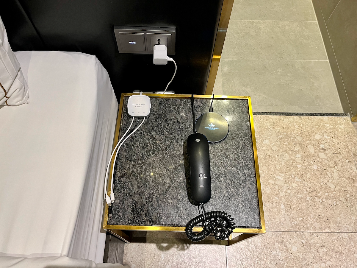 Nachttisch mit einem Telefon und Ladegerät im Hotelzimmer.