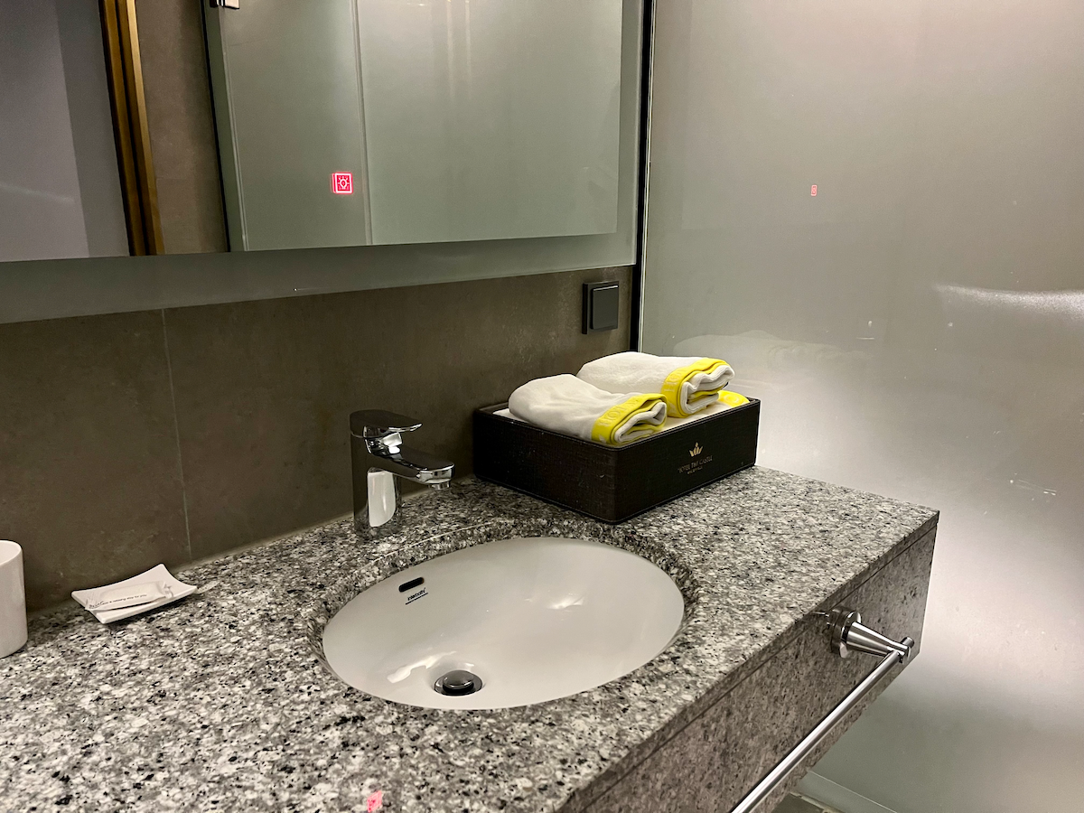 Großes Waschbecken mit Spiegel und kleinen Handtüchern im Hotelbadezimmer.