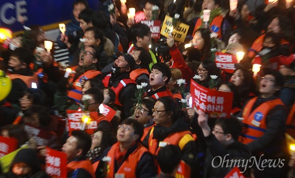 韩国首尔街头的烛光抗议游行，抗议者们手持标语反对朴槿惠政府。
